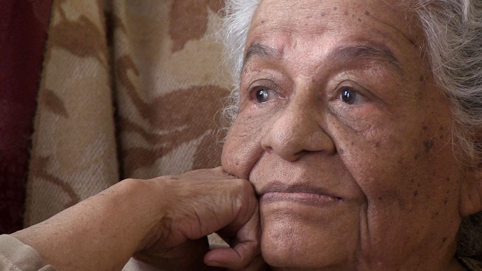 A close up of Mama Icha, an elderly woman with white hair and brown skin.